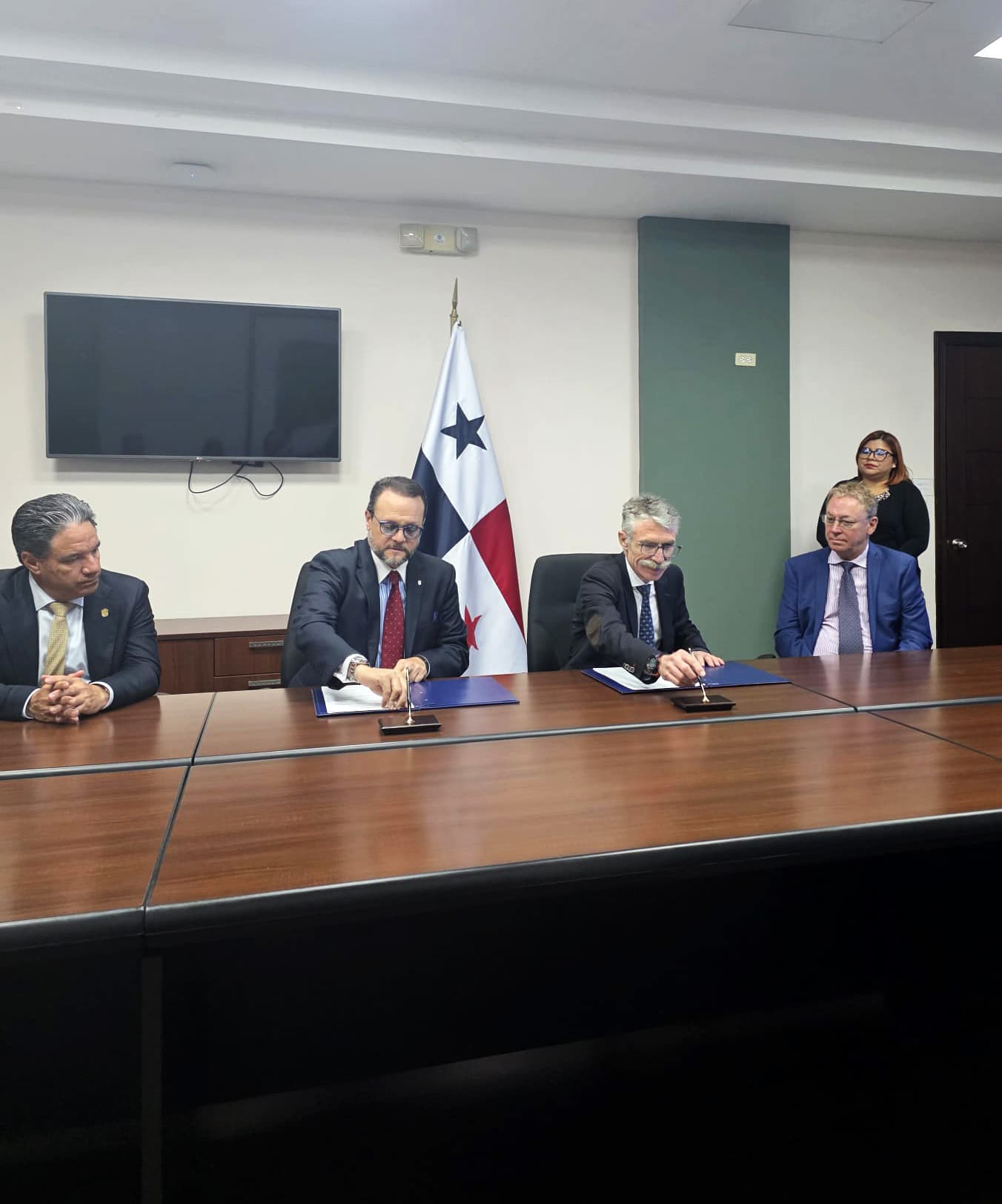 Officials seated at a signing table in front of the flag of Panama